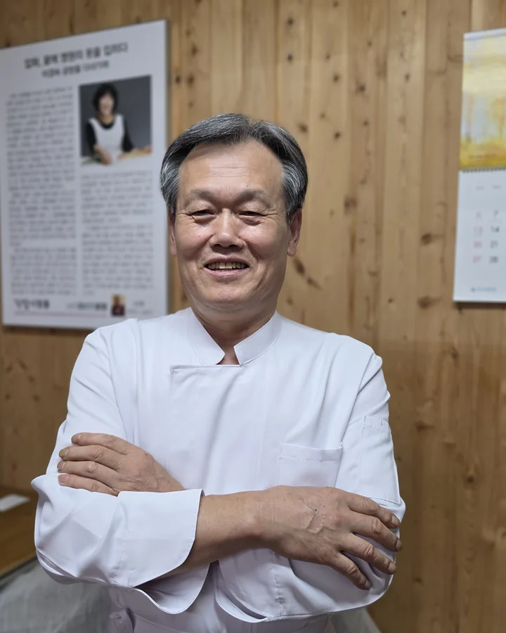 흰 조리복을 입고 팔짱 낀 채 웃는 김회준 사장님